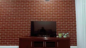 Un muro de ladrillo con un televisor sobre un pedestal de madera.