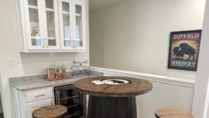 Una cocina con armarios blancos, una mesa redonda de madera y tres taburetes.