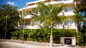 A modern hotel with a white facade, multiple balconies, and lush tropical landscaping. - Grand Sirenis (Akumal)