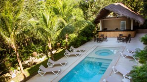 A pool area with lounge chairs and a bar. - Grand Sirenis (Akumal)