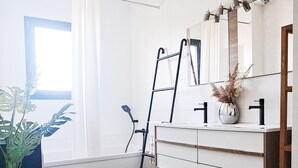 Une salle de bain moderne avec un meuble-lavabo blanc, un grand miroir et un tapis marron.