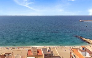 Eine Küstenansicht mit Strand, Gebäuden und einem Leuchtturm in der Ferne.