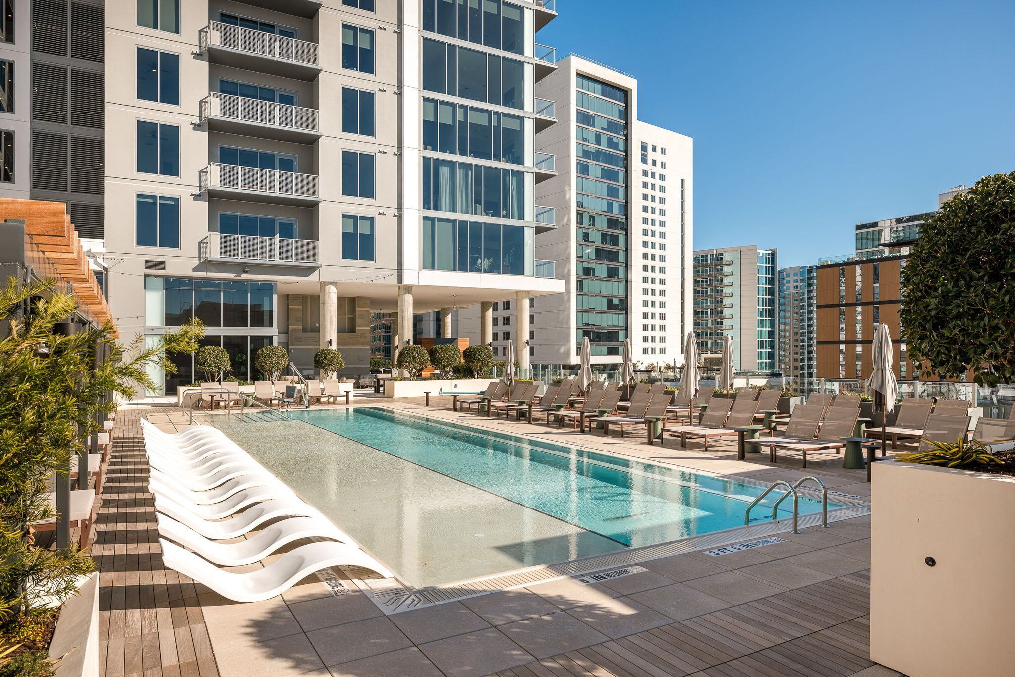 Ein modernes Hotel mit einem Infinity-Pool auf dem Dach, Liegestühlen und freiem Blick auf die Stadtlandschaft.