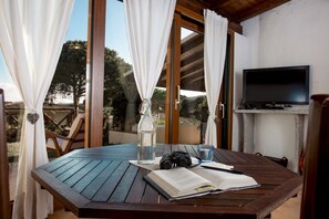Une table en bois, sur laquelle se trouvent un livre, une bouteille et une paire de lunettes.