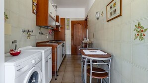 A compact kitchen with a washing machine, a small dining table, and a wooden door. - GuestHost - Spacious 81 sqm apartment in Taormina, ideal for 6 guests. Featuring two terraces from which to enjoy breathtaking sea views, this accommodation offers a unique experience. Perfectly situated just a short walk from the vibrant center of Taorm (Taormina)