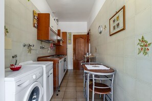 A compact kitchen with a washing machine, a small dining table, and a wooden door.
