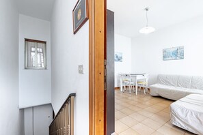 A modern interior with a staircase, a dining area with a table and chairs, and a white sofa.
