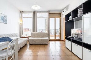 A modern apartment with a dining area, a sofa, a TV, and a balcony.