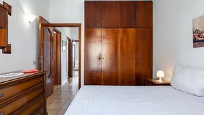 A bedroom with a large wooden wardrobe, a bed with white bedding, a dresser, and a nightstand with a lamp. - GuestHost - Spacious 81 sqm apartment in Taormina, ideal for 6 guests. Featuring two terraces from which to enjoy breathtaking sea views, this accommodation offers a unique experience. Perfectly situated just a short walk from the vibrant center of Taorm (Taormina)