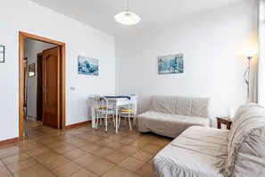Ein Zimmer mit Esstisch, zwei Stühlen, einer Couch, einer Lampe und zwei Bildern an der Wand.