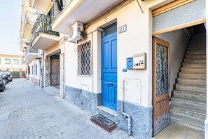 Une rue étroite avec une porte bleue, un escalier et une moto garée.