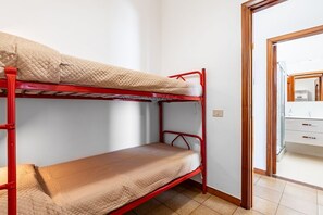 A bunk bed with a quilted mattress, a wooden door frame, and a white wall.
