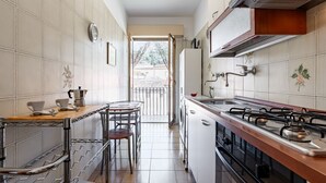 A narrow kitchen with a gas stove, a coffee maker, and a sink. - GuestHost - Spacious 81 sqm apartment in Taormina, ideal for 6 guests. Featuring two terraces from which to enjoy breathtaking sea views, this accommodation offers a unique experience. Perfectly situated just a short walk from the vibrant center of Taorm (Taormina)