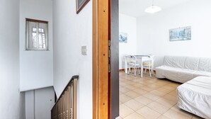 A modern interior with a staircase, a dining area with a table and chairs, and a white sofa. - GuestHost - Spacious 81 sqm apartment in Taormina, ideal for 6 guests. Featuring two terraces from which to enjoy breathtaking sea views, this accommodation offers a unique experience. Perfectly situated just a short walk from the vibrant center of Taorm (Taormina)
