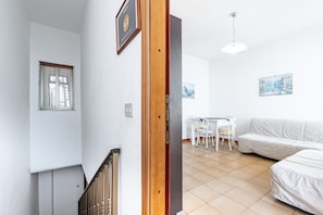 Ein modernes Interieur mit einer Treppe, einem Essbereich mit Tisch und Stühlen sowie einem weißen Sofa.