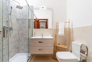 A bathroom with a shower, toilet, sink, and a mirror.