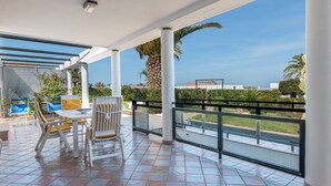 Un espace extérieur abrité, doté d’une table et de chaises, d’une rambarde et offrant une vue sur le paysage.