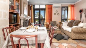 Un coin repas avec une nappe à carreaux, des chaises en bois et un canapé en osier agrémenté de coussins.