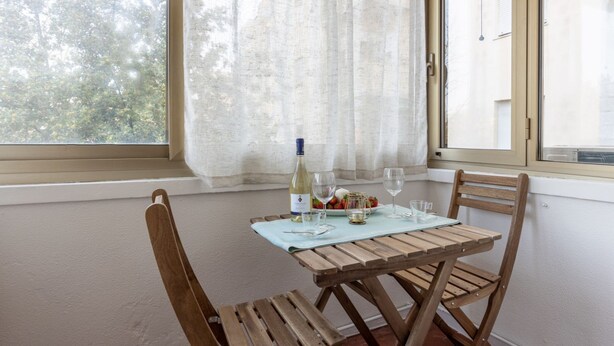 Een eettafel met stoelen, een fles wijn en glazen voor twee personen.