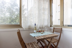 A dining table with chairs, a bottle of wine, and glasses set for two.