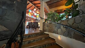 Una escalera de piedra con barandilla de madera que conduce a un comedor con sillas y mesa de madera.
