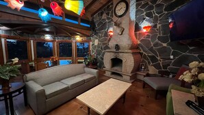 Una sala de estar acogedora con chimenea de piedra, un sofá, una mesa de centro y un comedor con mesa y sillas.