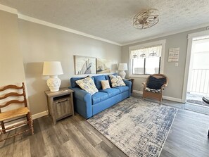 Ein Wohnzimmer mit einem blauen Sofa, einem Holztisch und einem Korbstuhl.
