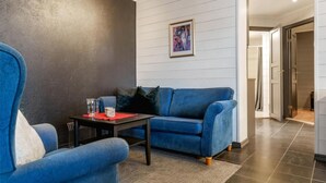 Ein modernes Wohnzimmer mit einem blauen Sofa, einem kleinen Tisch mit einer roten Unterlage und einem gerahmten Bild an der Wand.