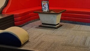 Une pièce avec un mur d’accent rouge, un canapé, une petite table et un sol recouvert d’une moquette.