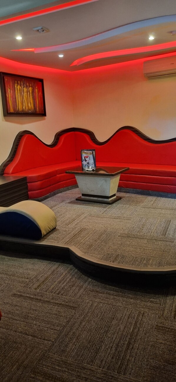 A room with a red accent wall, a sofa, a small table, and a carpeted floor.