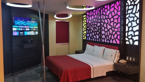 Une chambre d’hôtel moderne équipée d’un lit, d’un téléviseur fixé au mur et d’une cloison décorative.