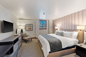 A hotel room with a bed, bedside table, lamp, desk, chair, and a TV. - The Sebastian at affordable rates! Vail Village Location with Parking - 5 Star Amenities + Services (Vail)
