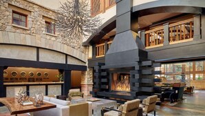 Un hall d’entrée spacieux avec un mur en pierre, une cheminée et des coins salon confortables.