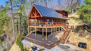 A log cabin with a deck and a staircase leading to a second level.