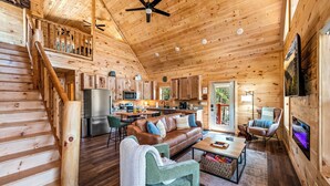 A spacious cabin with a wooden interior, a kitchen, a dining area, and a living room with a fireplace.