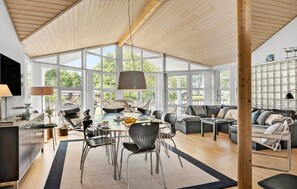 En rummelig opholdsstue med et stort vindue, et spisebord og moderne møbler.