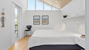 A modern bedroom with a large bed, a chair, two framed pictures, a plant, and a ceiling with wooden beams. - Pet friendly home in Farsø with WiFi (Farsø)