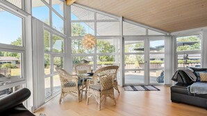 A spacious room with large windows, a dining area with wicker chairs, a black leather sofa, and a wooden ceiling. - Pet friendly home in Farsø with WiFi (Farsø)