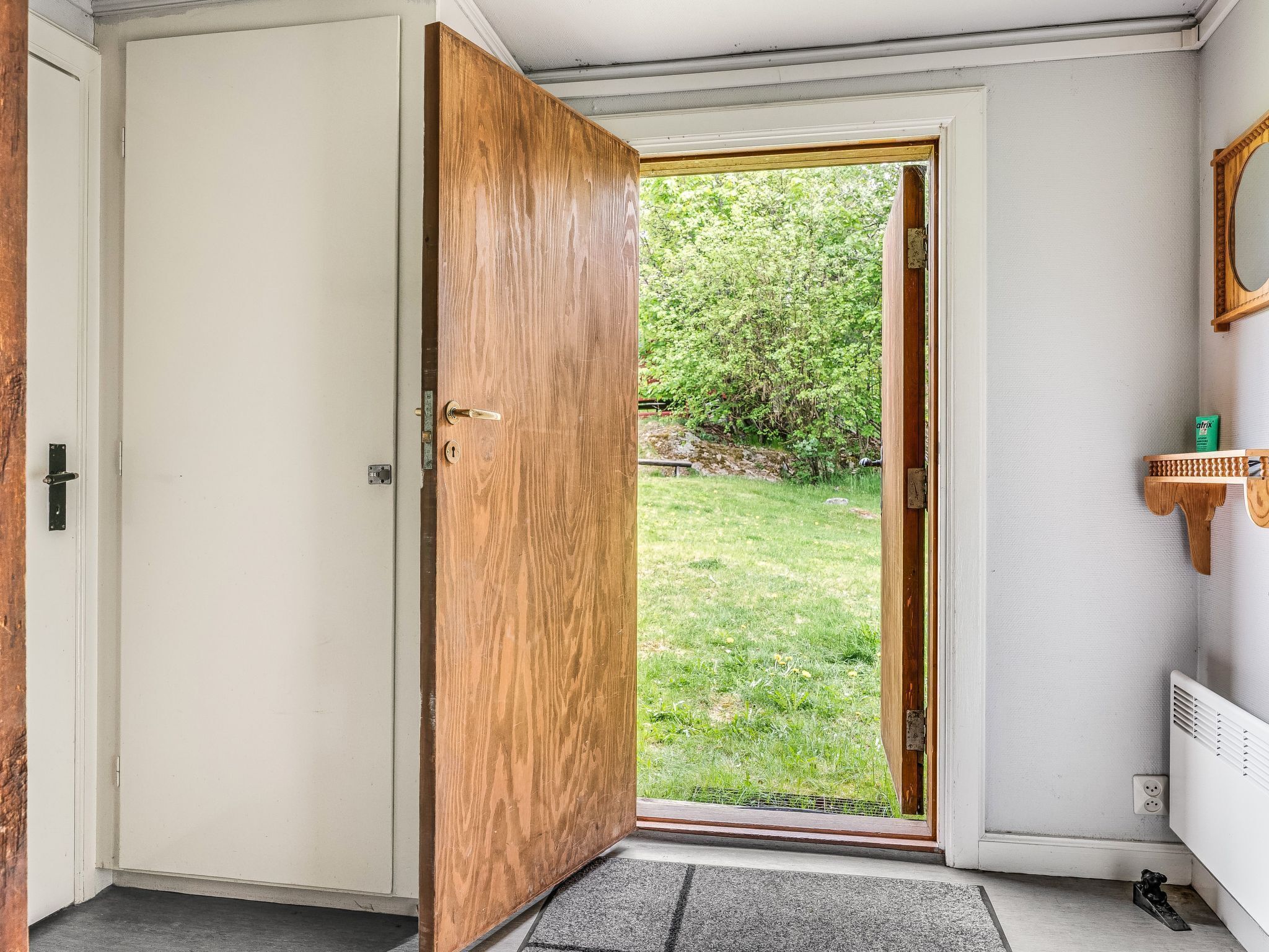 Una habitación con una puerta de madera, una ventana pequeña y un radiador.