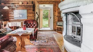 A cozy log cabin interior with a fireplace, leather armchair, wooden table, and a large rug. - Vacation home Alice by Interhome (Tällberg)