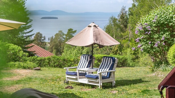 Two lounge chairs with a beach view, a beach umbrella, and a lamp post. - Vacation home Alice by Interhome (Tällberg)