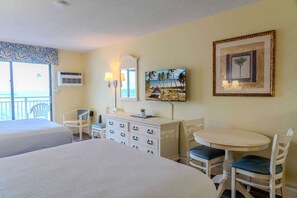 Camera d'albergo con due letti, una scrivania, una sedia, un televisore e un quadro appeso al muro.