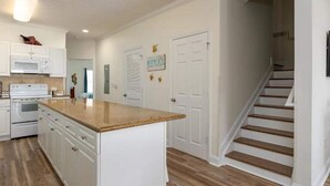A kitchen with white cabinets, a granite countertop, and a wooden staircase.