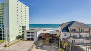 A coastal hotel with multiple buildings, a parking area, and a view of the ocean.
