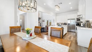 A modern kitchen with white cabinets, stainless steel appliances, and a wooden dining table with chairs.