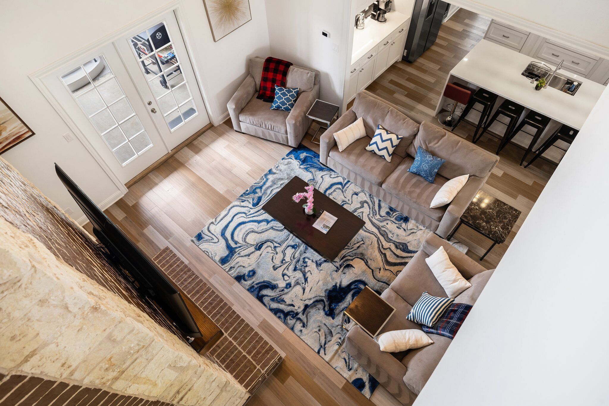 Amplia sala de estar con un tapete grande y estampado, varios sofás y una zona de cocina con barra.