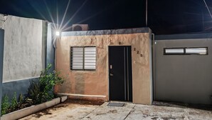 Un edificio con una puerta negra, número 225, y un ventanal pequeño.