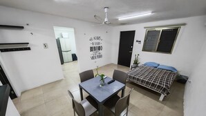 Una habitación pequeña con una mesa de comedor, sillas, cama y ventilador de techo.