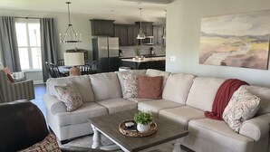 Ein Wohnzimmer mit Ecksofa, Couchtisch und Essbereich mit Stühlen und Tisch.