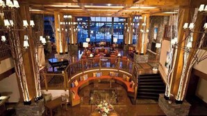 A spacious lobby with a curved seating area, a central table with flowers, and a staircase leading to upper levels. - Spruce  Peak resort Ski In/Outwith great views (Stowe)